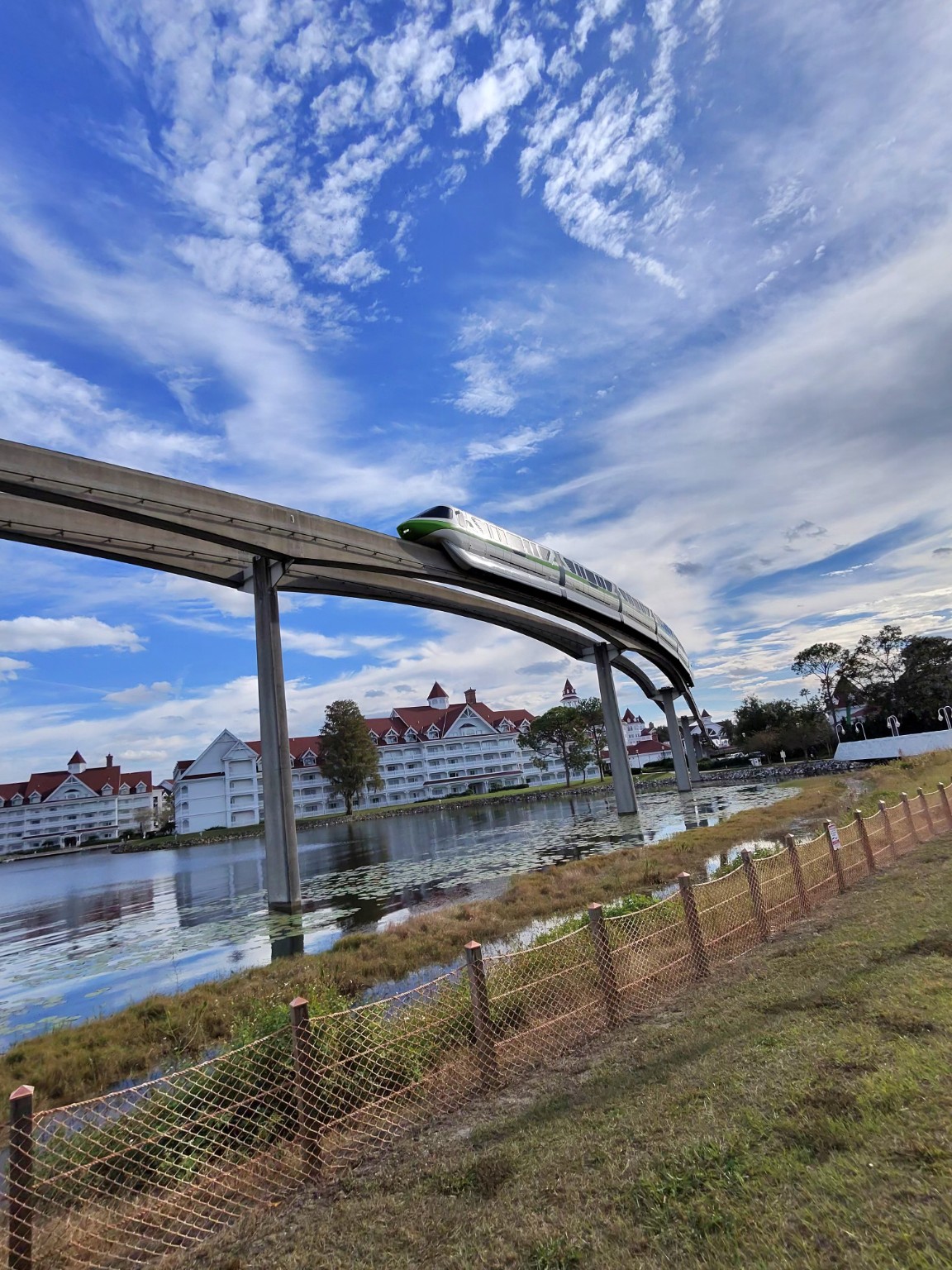 A green-striped monorail passes the Grand Floridian on an elevated track.