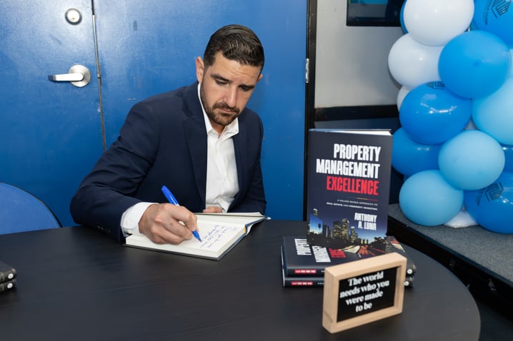 Anthony signing a copy of PME at a community event about Property Management Excellence